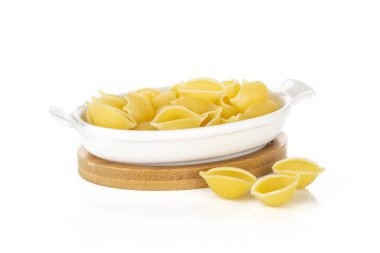 Beyaz arka plan üzerinde izole bir seramik güveç içinde bütün pişmemiş çiğ sarı makarna conchiglie değişiklik sürü