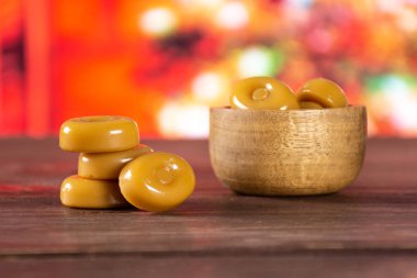 Bütün karamel krem şeker karamela çeşitli Noel ağacı kırmızı arka plan ile ahşap kase ile sürü