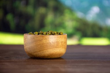 Bütün kuru yeşil mung fasulye arka planda ülke doğa ile ahşap kase ile sürü
