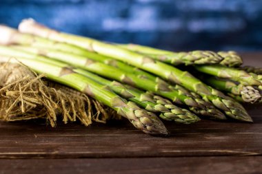 Bütün taze yeşil kuşkonmaz mızrak kahverengi ahşap üzerine Jüt kumaş ile sürü