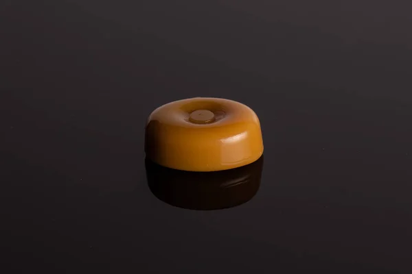 Eine Ganze Karamell Sahne Bonbon Sorte Butterscotch Auf Schwarzem Glas — Stockfoto