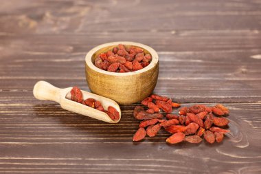 Kırmızı goji meyveleri kahverengi ahşap üzerine kurutulmuş