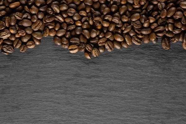 Grãos de café marrom escuro doce arábica em pedra cinza — Fotografia de Stock