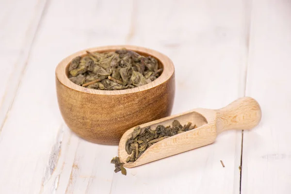 Trockener grüner Tee auf grauem Holz — Stockfoto