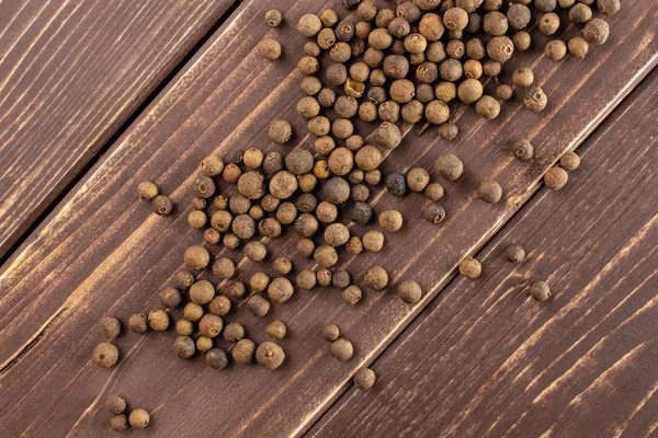 Bagas de pimenta seca em madeira marrom — Fotografia de Stock