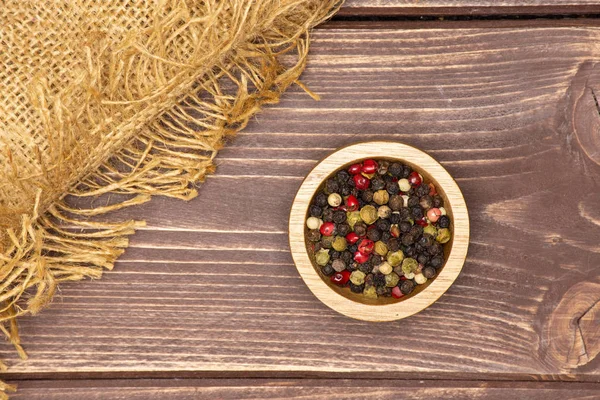 Cuatro colores de granos de pimienta sobre madera marrón — Foto de Stock