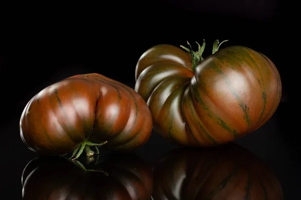 Frische dunkle Tomatenprimora isoliert auf schwarzem Glas — Stockfoto