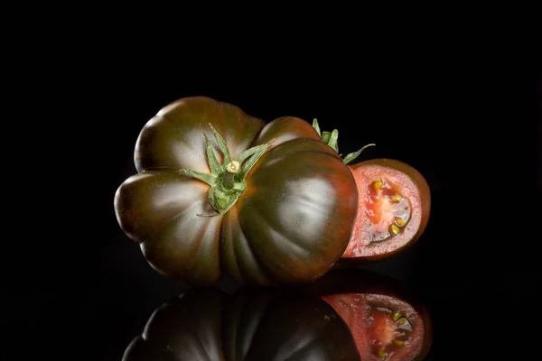 Frische dunkle Tomatenprimora isoliert auf schwarzem Glas — Stockfoto