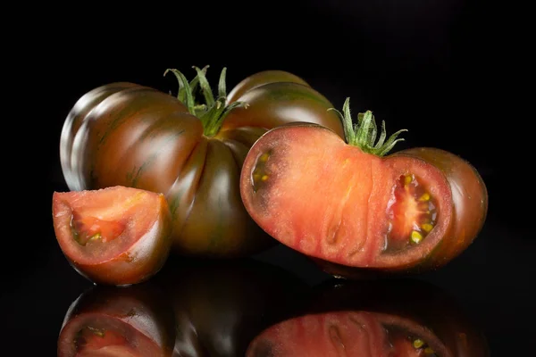 Fresh dark tomato primora isolated on black glass — Stock Photo, Image