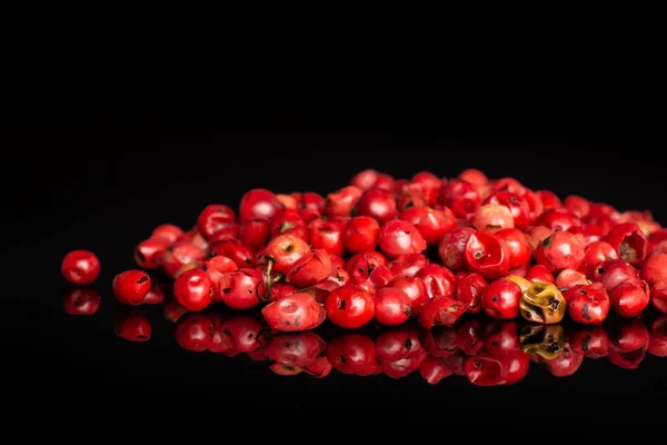 Pink peruvian pepper isolated on black glass