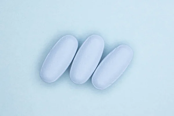 Blue medical pills on light blue — Stock Photo, Image