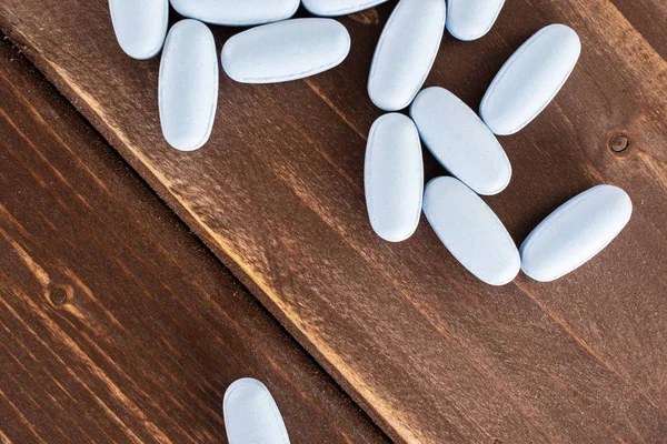 Blue medical pills on brown wood — Stock Photo, Image