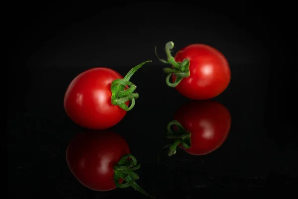 Rote Kirschtomate isoliert auf schwarzem Glas — Stockfoto