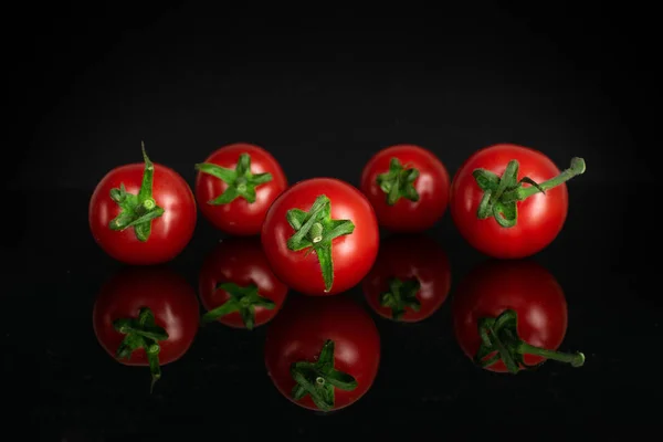 Rote Kirschtomate isoliert auf schwarzem Glas — Stockfoto