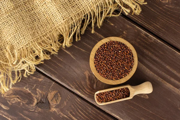 Red quinoa seeds on brown wood