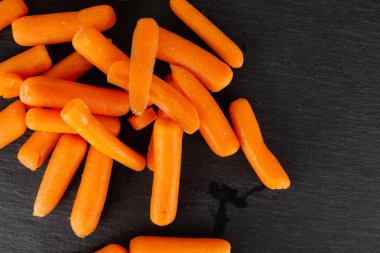 Peeled baby carrot on grey stone clipart