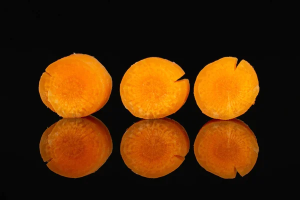 Peeled baby carrot isolated on black glass — Stock Photo, Image