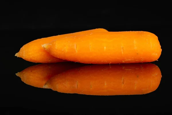 Peeled baby carrot isolated on black glass — Stock Photo, Image