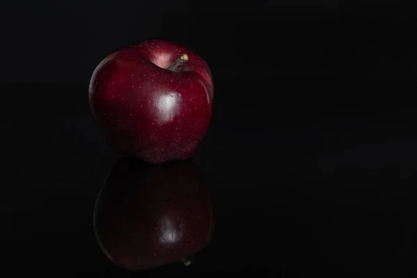 Jabłko czerwone pyszne izolowane na czarnym szkle — Zdjęcie stockowe