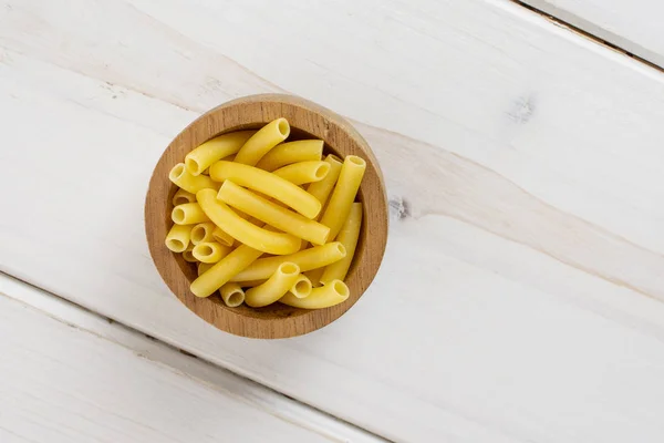 Raw macaroni pasta on grey wood — Stock Photo, Image