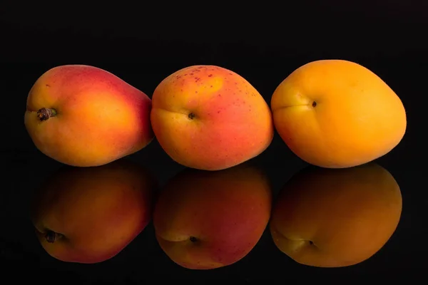 Verse oranje abrikoos geïsoleerd op zwart glas — Stockfoto