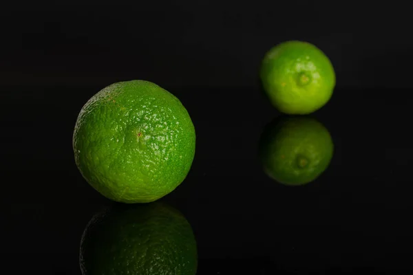 Fresh green lime isolated on black glass