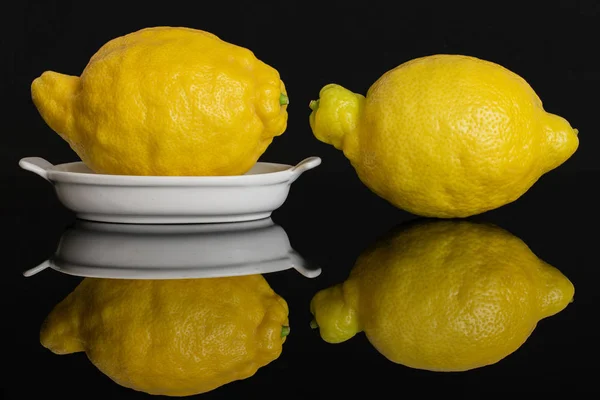 Fresh yellow lemon isolated on black glass