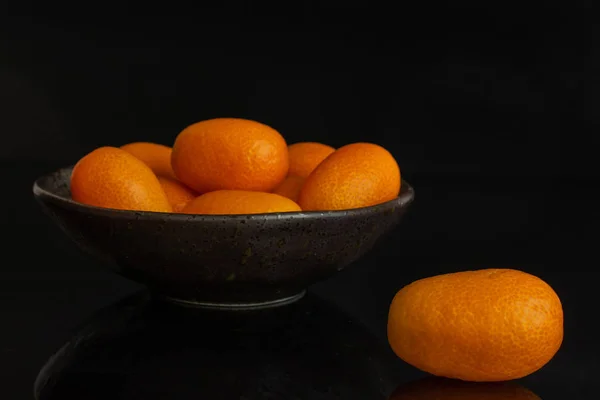 Fresh orange kumquat isolated on black glass — Stock Photo, Image