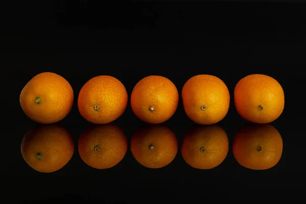 Kumquat laranja fresco isolado em vidro preto — Fotografia de Stock