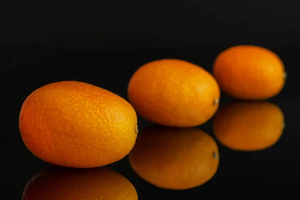 Frischer orange Kumquat isoliert auf schwarzem Glas — Stockfoto