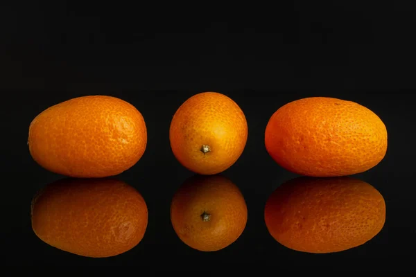 Kumquat naranja fresco aislado en vidrio negro —  Fotos de Stock