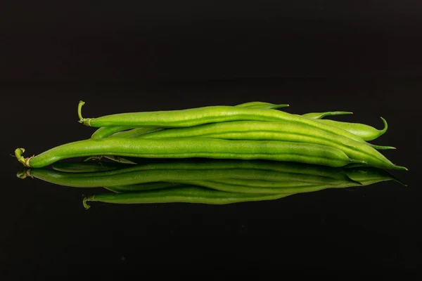 Frische grüne Bohnen isoliert auf schwarzem Glas — Stockfoto