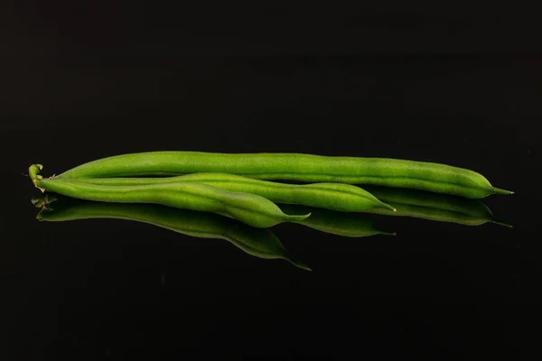 Färska gröna bönor isolerade på svart glas — Stockfoto