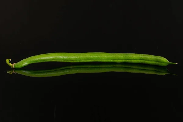 Frische grüne Bohnen isoliert auf schwarzem Glas — Stockfoto