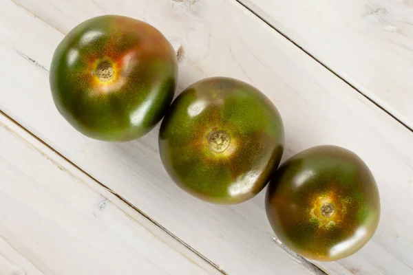 Tomate vermelho esverdeado sobre madeira cinzenta — Fotografia de Stock