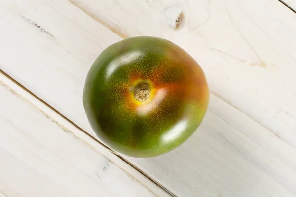 Tomate vermelho esverdeado sobre madeira cinzenta — Fotografia de Stock