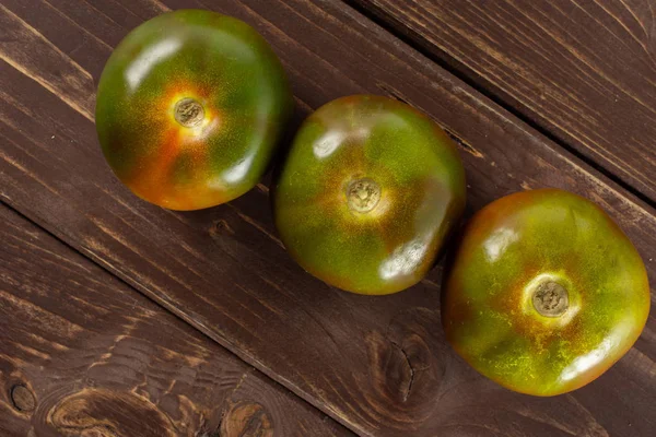 Tomate vermelho esverdeado em madeira marrom — Fotografia de Stock