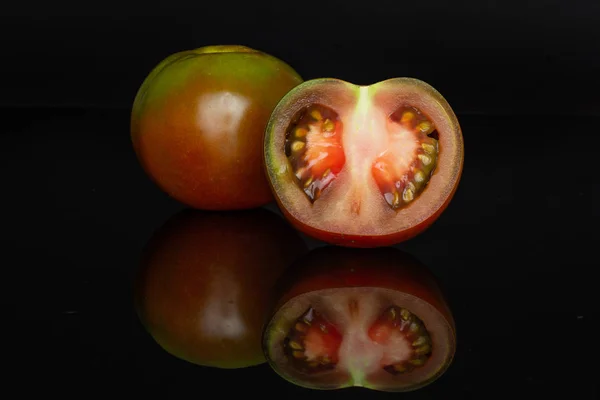Tomate rojo verdoso aislado en vidrio negro —  Fotos de Stock