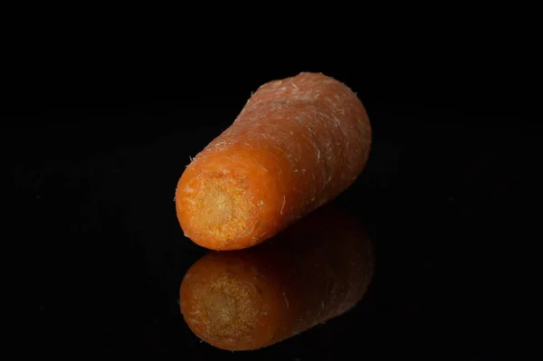 Orange Baby-Karotte isoliert auf schwarzem Glas — Stockfoto