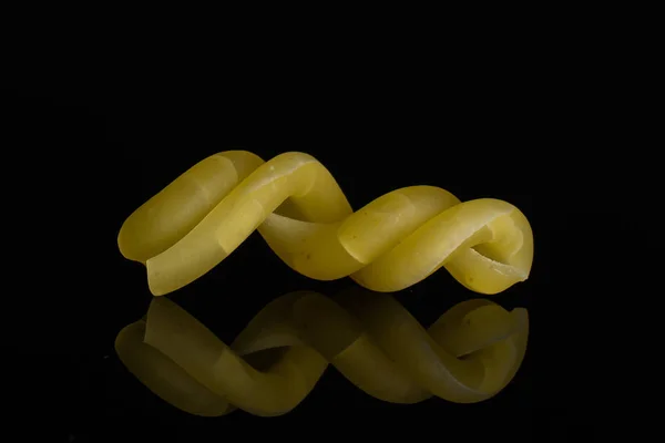 Rå pasta Gemelli isolerad på svart glas — Stockfoto