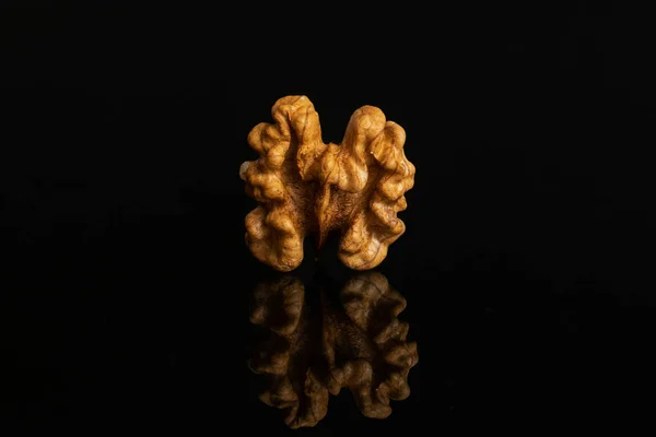 Ripe brown walnut isolated on black glass — Stock Photo, Image