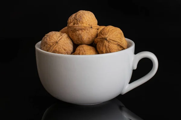 Ripe brown walnut isolated on black glass — Stock Photo, Image