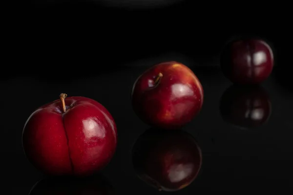 Prune rouge mûre isolée sur verre noir — Photo