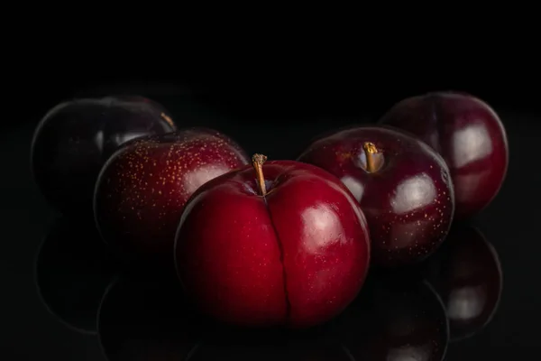 Ripe red plum isolated on black glass — Stock Photo, Image