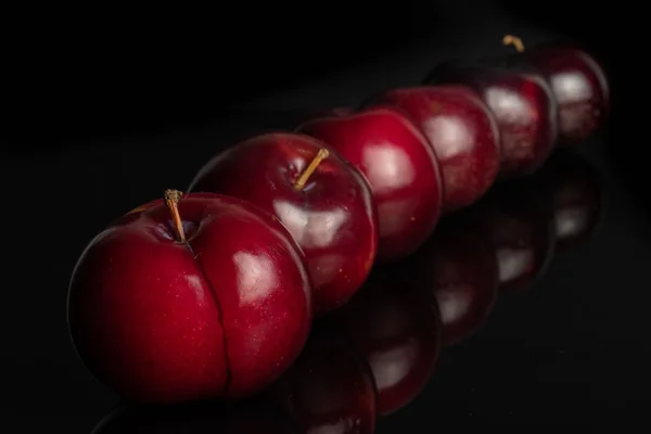 Ripe red plum isolated on black glass — Stock Photo, Image