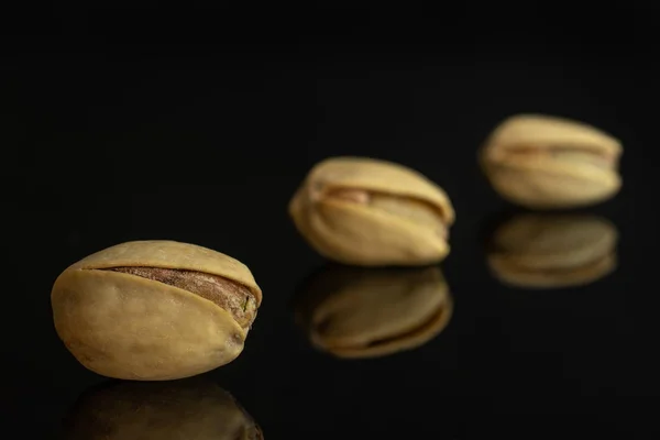 Groene gezouten pistache geïsoleerd op zwart glas — Stockfoto