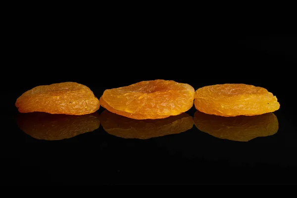 Suszone pomarańczowe morele izolowane na czarnym szkle — Zdjęcie stockowe