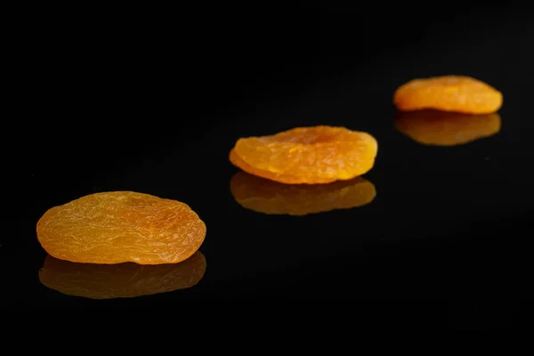 Suszone pomarańczowe morele izolowane na czarnym szkle — Zdjęcie stockowe