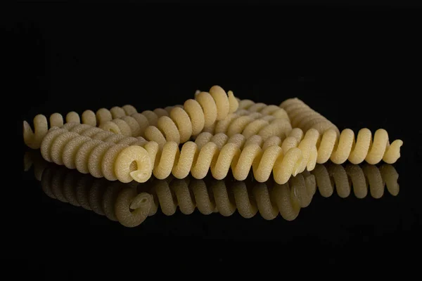 Ham makarna fusilli bucati siyah cam izole — Stok fotoğraf