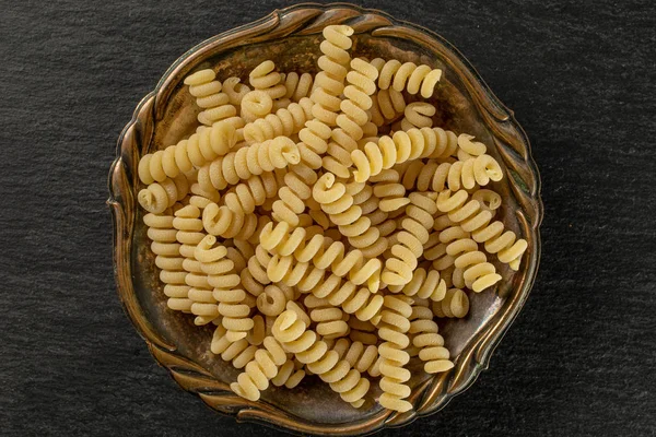 Rohe Pasta fusilli bucati auf grauem Stein — Stockfoto